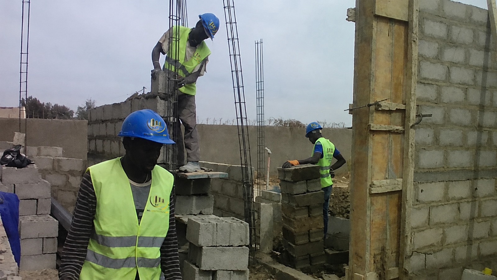 L'équipe de Rio Construction BTP montant un mur en agglos avec poteaux ferraillés, sur un chantier à Rufisque